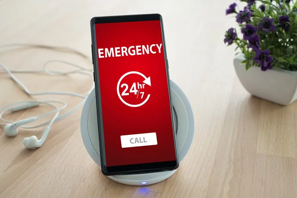 Emergency call concept. Emergency call concept. Mobile smartphone is placed on a wireless fast charger. 24 Hour Welding.